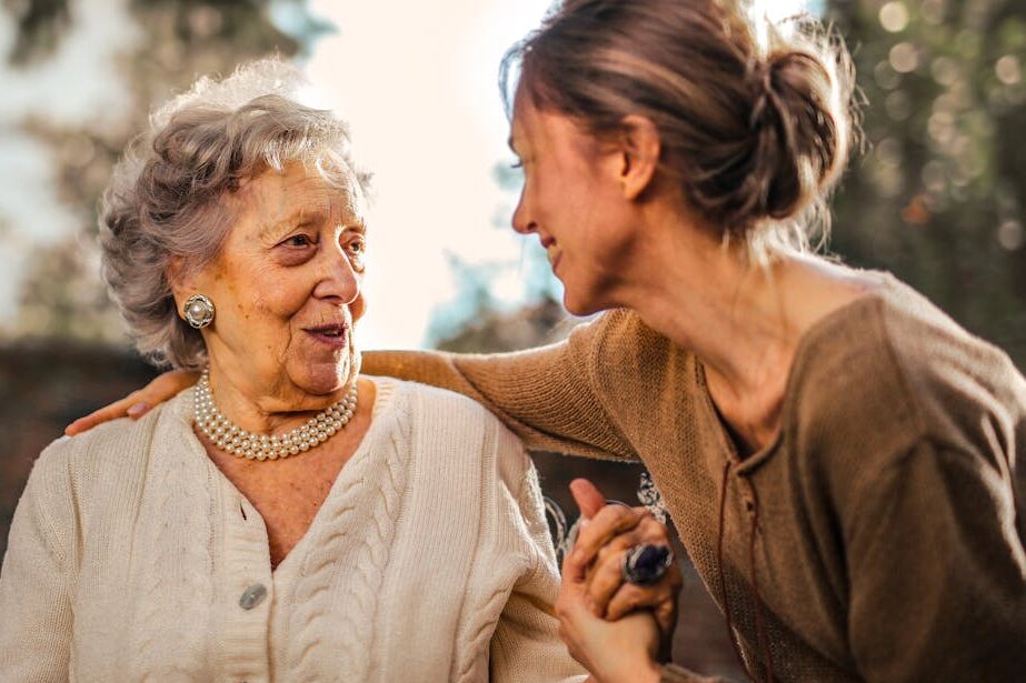 Joyful adult daughter greeting happy surprised senior mother in garden