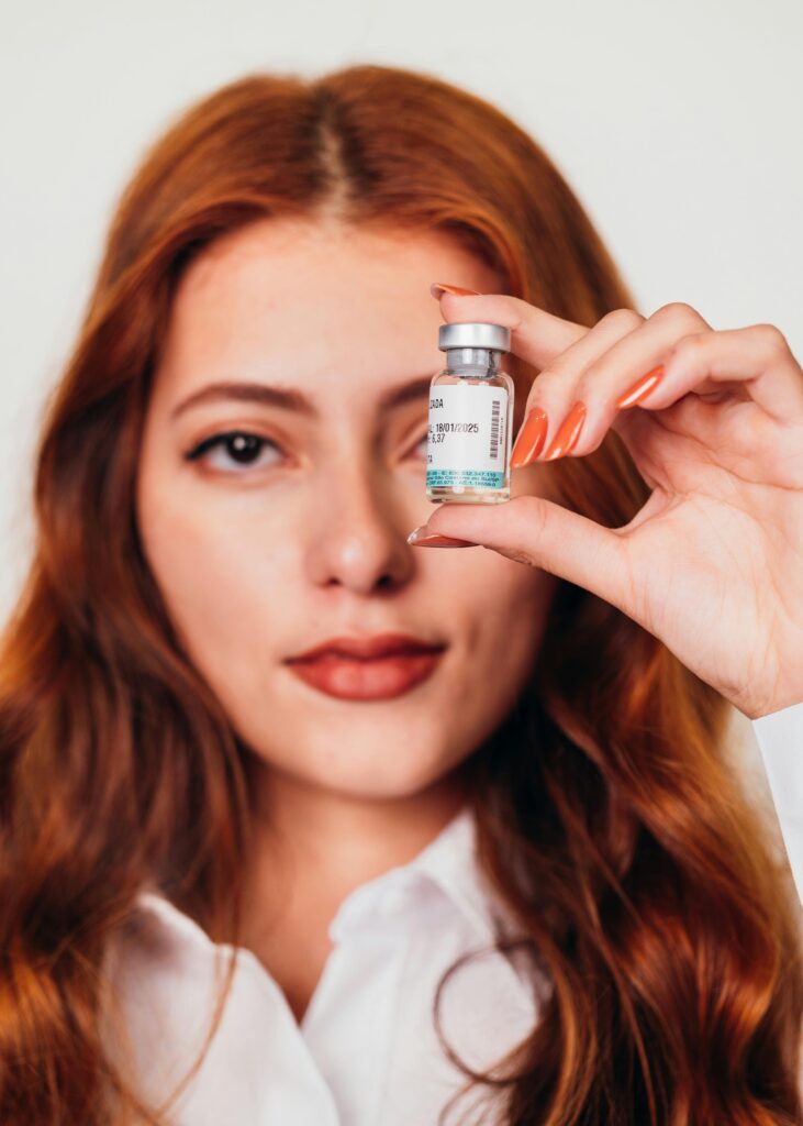 Close-up of a young woman holding a vaccine bottle. Focus on health and medicine.