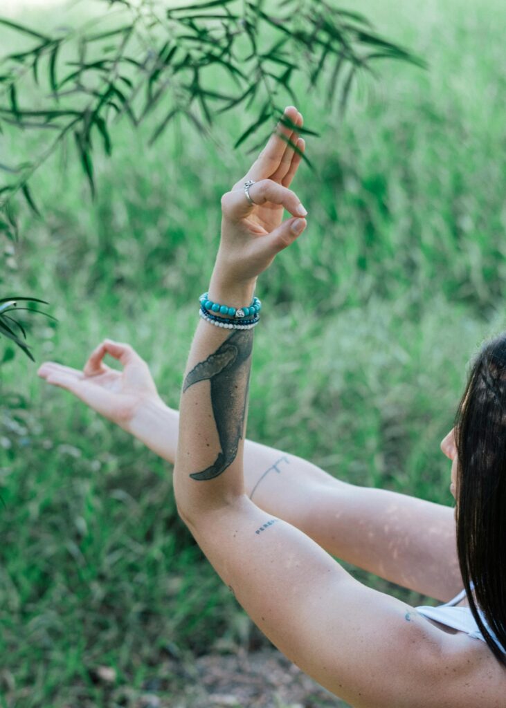 From above side view of crop concentrated female with hands in gyan mudra meditating in park near tree